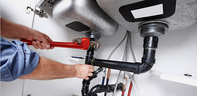 plumber with wrench repairing sink